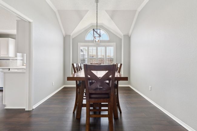 Dining space featuring dark wood-style floors, lofted ceiling, ornamental molding, and baseboards | Image 9