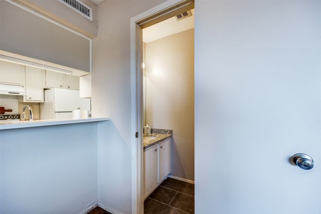 Kitchen passthrough and half bath, with granite counter tops and tile flooring | Image 18