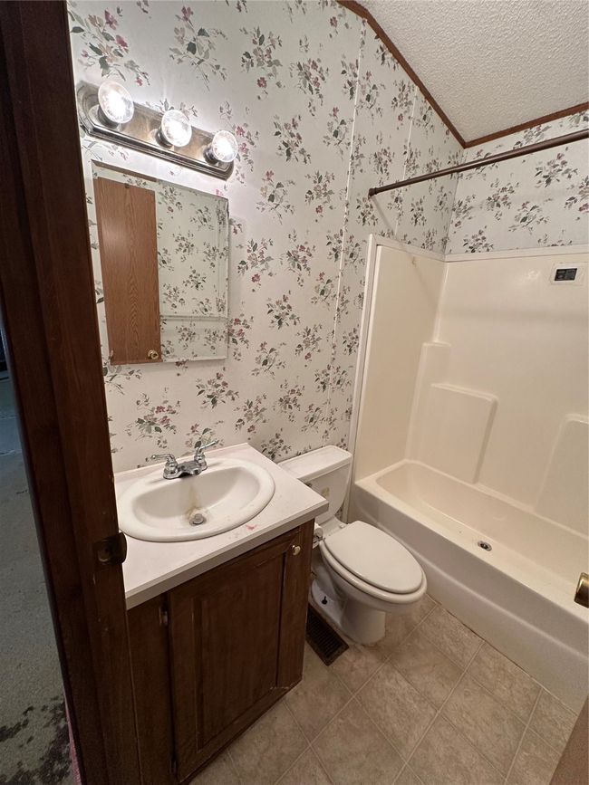 Full bath with wallpapered walls, vanity, toilet, a textured ceiling, and shower combination | Image 29