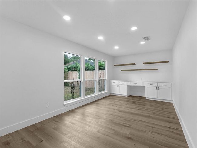 Bright, spacious room with large windows, hardwood floors, built-in shelving, and cabinets. Ideal for a home office or study. | Image 10