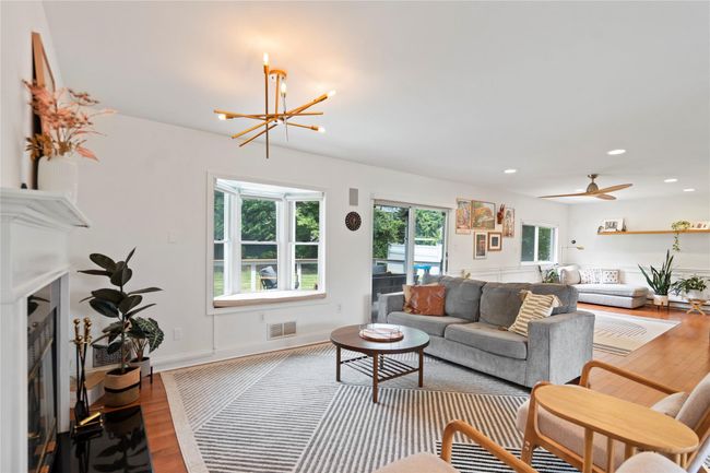 Living room with wood finished floors, a chandelier, a fireplace, and recessed lighting | Image 7
