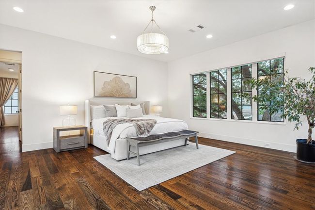 PRIMARY BEDROOM SUITE. Located at the back of the home, the primary bedroom suite exudes serenity and calm. With three walls of windows, enjoy the abundant natural light or press the remote to lower the shades. | Image 15