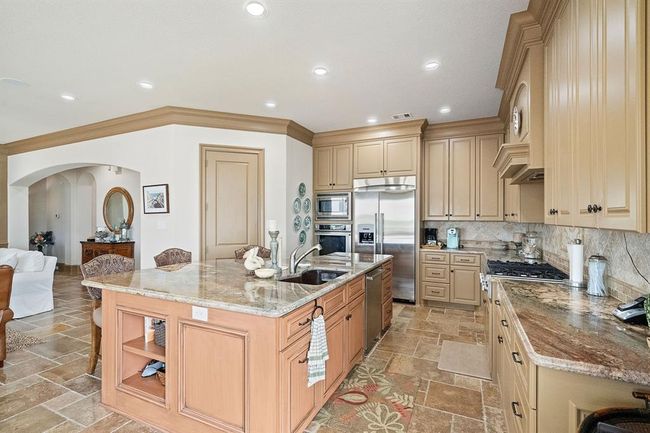 The island kitchen impresses with granite countertops, custom cabinets with plenty of storage and breakfast bar | Image 16