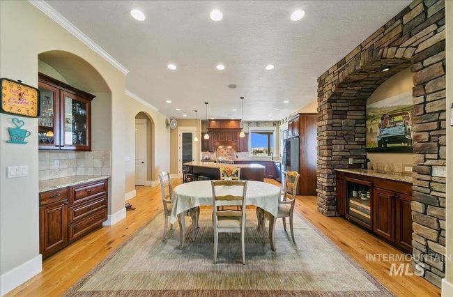 Dining space featuring crown molding, recessed lighting, light wood-style flooring, arched walkways, and wine cooler | Image 8