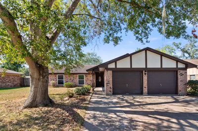 Charming front exterior of 233 Petunia Street showcasing mature trees & a well-maintained exterior with a 2-car attached garage. The inviting entryway leads into this recently updated 3-bedroom, 2-bathroom home situated on a 0.22-acre lot in Lake Jackson. | Image 1