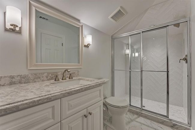 The full bath on the second floor showcases a walk-in shower with an elegant herringbone tile pattern, a sleek vanity topped with a quartz countertop, and romantic lighting that adds a warm, inviting ambiance. | Image 36
