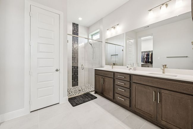 Full bathroom with double vanity, a stall shower, tile patterned floors, and a walk in closet | Image 16