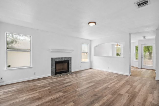 Unfurnished living room featuring visible vents, a wealth of natural light, and wood finished floors | Image 7