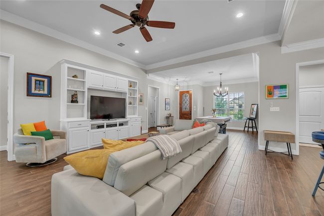 Living area with dark wood-style flooring, ceiling fan, baseboards, ornamental molding, and recessed lighting | Image 10