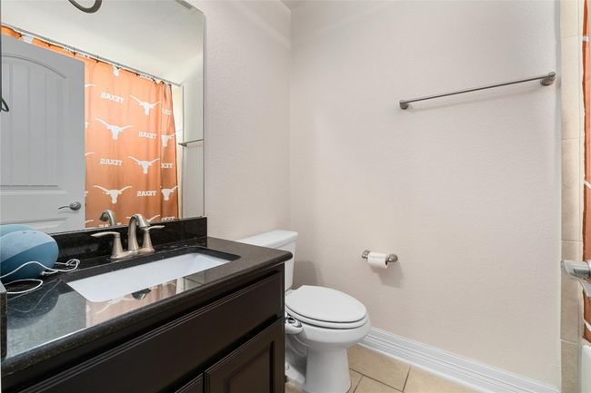 Bathroom featuring a shower with shower curtain, baseboards, toilet, tile patterned floors, and vanity | Image 25
