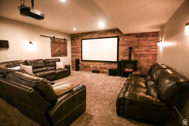 Carpeted home theater room with a barn door, wood walls, and a wood stove | Image 60