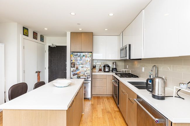 Kitchen featuring stainless steel appliances, light wood-style flooring, a sink, modern cabinets, and a center island | Image 4