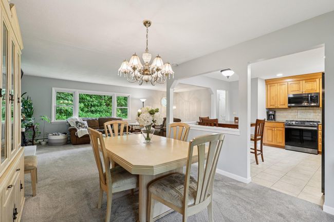 Dining area featuring light colored carpet, a chandelier, and light tile patterned floors | Image 7