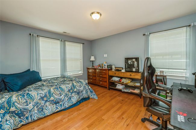 Bedroom with wood finished floors, multiple windows, and an office area | Image 11