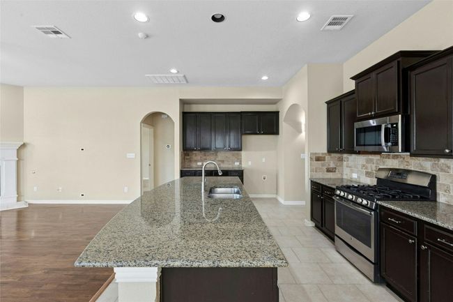 Kitchen featuring appliances with stainless steel finishes, a sink, arched walkways, tasteful backsplash, and recessed lighting | Image 7