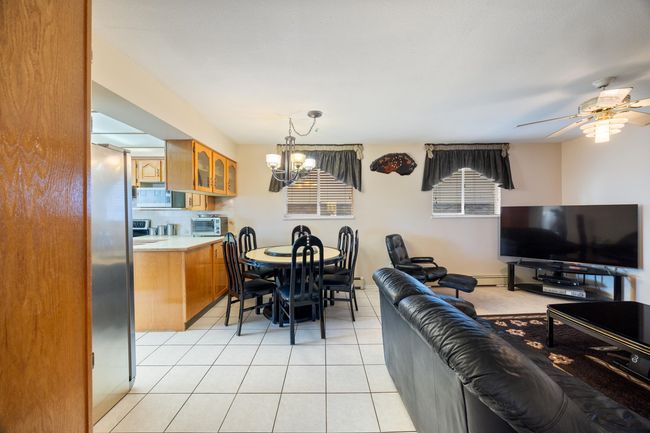 Dining space featuring light tile patterned flooring, a toaster, baseboard heating, and ceiling fan with notable chandelier | Image 17