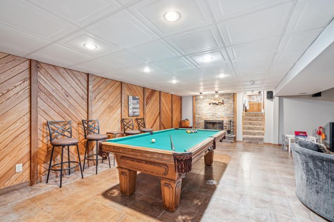 Expansive basement rec room with a floor to ceiling stone fireplace and ample room for entertaining friends and family | Image 33