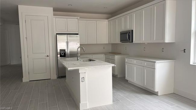 Chef's kitchen with quartz countertops, soft-close cabinets and drawers, and Whirlpool stainless steel appliances including gas oven, range microwave, dishwasher, and 36" side-by-side refrigerator | Image 4