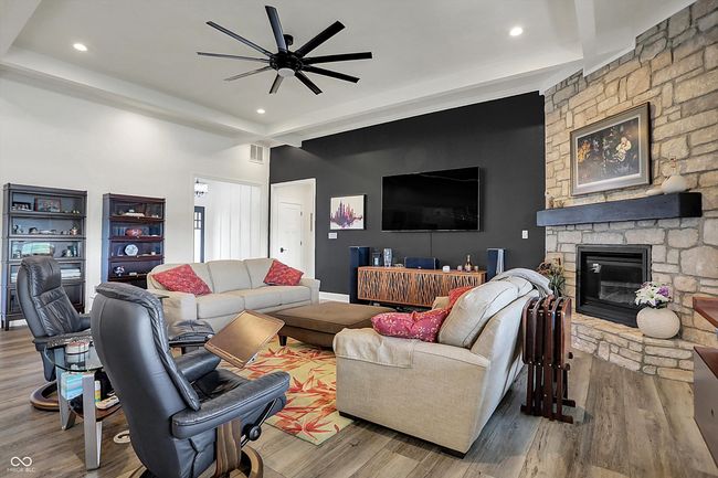 living area with recessed lighting, wood finished floors, visible vents, a stone fireplace, and ceiling fan | Image 11