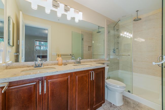 Bathroom featuring a stall shower, double vanity, and toilet | Image 22