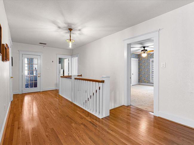 Stair landing with hardwood floors provides entrance to bedroom areas. | Image 29
