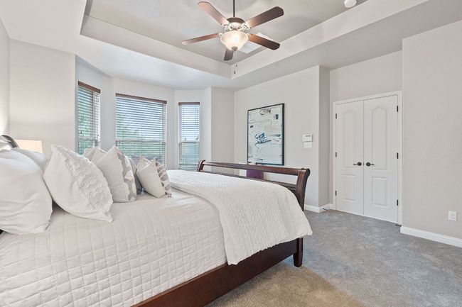 Carpeted bedroom with a tray ceiling, baseboards, a ceiling fan and bay window | Image 20
