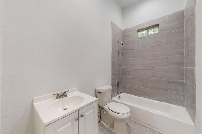 Full bathroom featuring tile flooring, vanity, toilet, and tiled shower / bath combo | Image 24