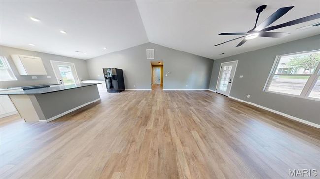 Unfurnished living room featuring lofted ceiling, a ceiling fan, light wood-type flooring, and baseboards | Image 6