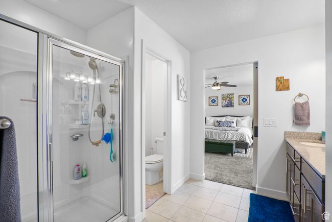 Full bath with a shower stall, tile patterned flooring, a ceiling fan, vanity, and ensuite bathroom | Image 14