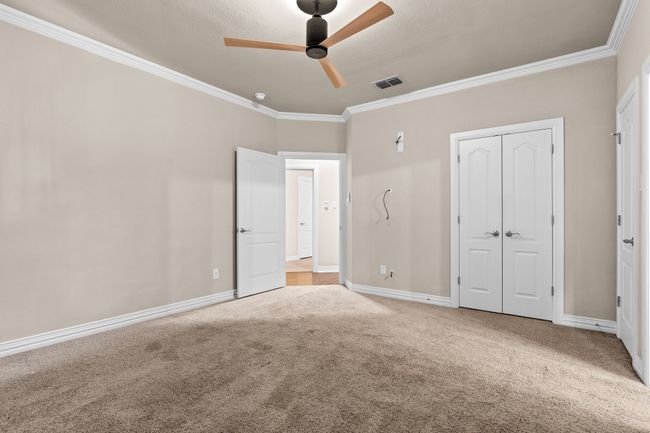 Unfurnished bedroom featuring ornamental molding, carpet floors, a closet, and a ceiling fan | Image 31