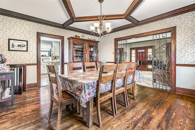 Dining area with wallpapered walls, an inviting chandelier, a wainscoted wall, dark wood finished floors, and ornamental molding | Image 15