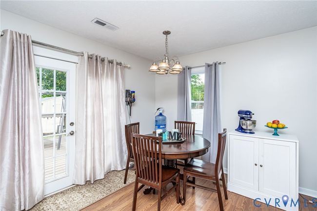 Dining area with wood finished floors and a chandelier | Image 9