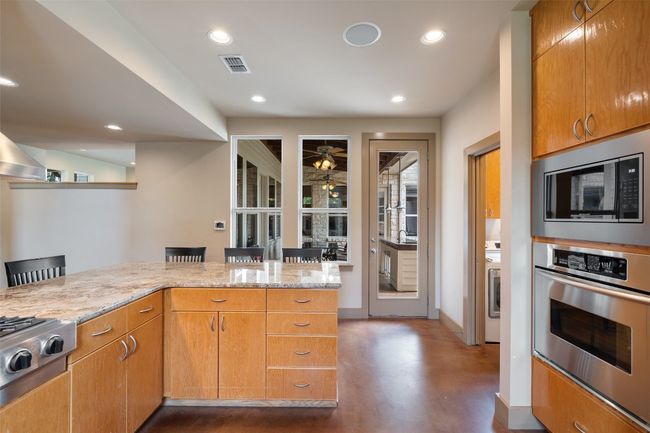 Kitchen featuring stainless steel appliances, light stone countertops, concrete floors, recessed lighting, and baseboards | Image 14