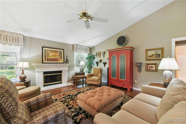 Living area with ceiling fan, wood finished floors, a glass covered fireplace, and high vaulted ceiling | Image 4