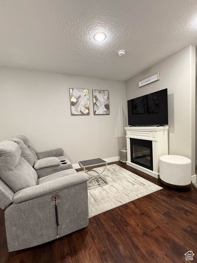 Living room with a textured ceiling, wood finished floors, and a glass covered fireplace | Image 12