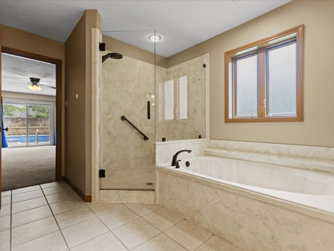 Master bathroom featuring a marble finish shower, tile patterned floors, a garden tub, and a textured ceiling | Image 28