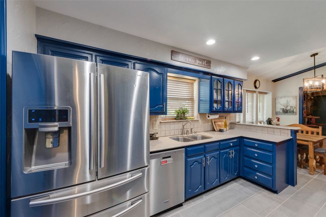 Kitchen featuring stainless steel appliances, a sink, a peninsula, blue cabinets, and light tile patterned floors | Image 18