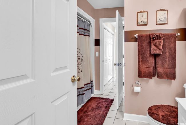 Bathroom with tile patterned floors, baseboards, curtained shower, and toilet | Image 17