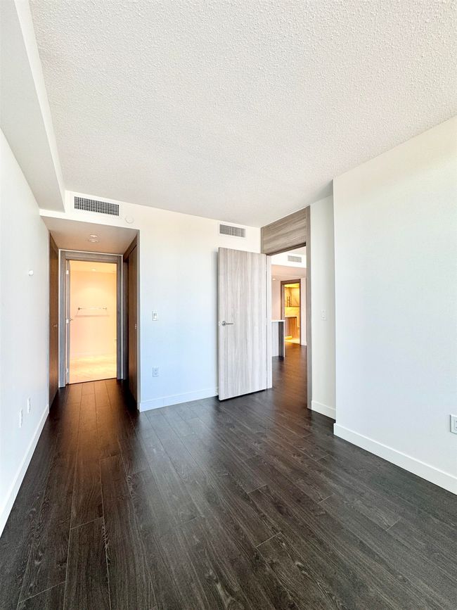 Unfurnished living room featuring baseboards, dark wood-type flooring, visible vents, and a textured ceiling | Image 14