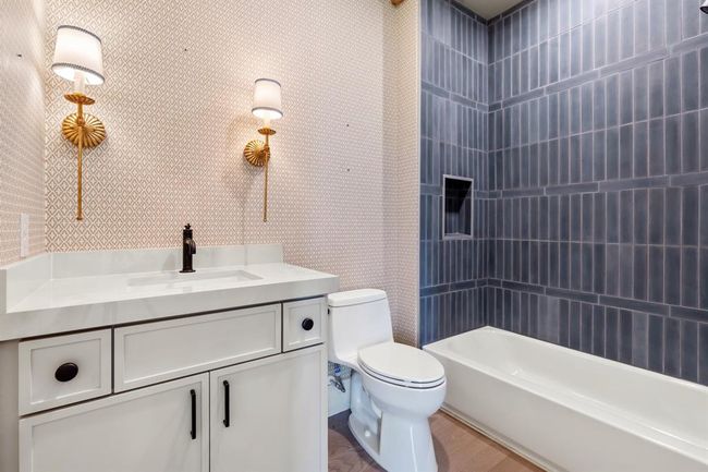 The vanity features a neutral counter top and is contrasted by a cement tile at the tub surround. | Image 30