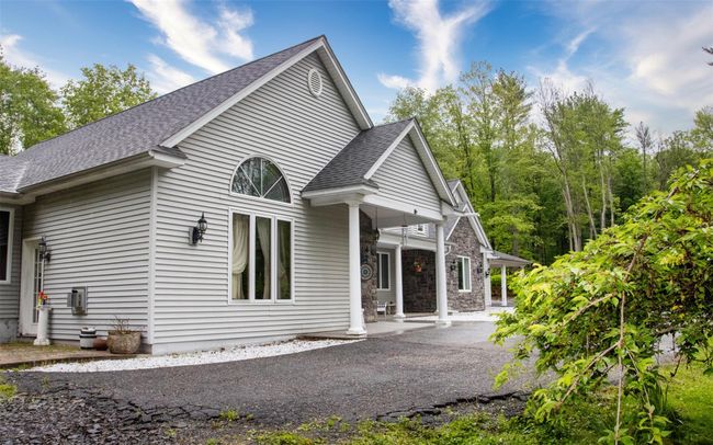 View of front facade with covered porch, roof with shingles, and stone siding | Image 6
