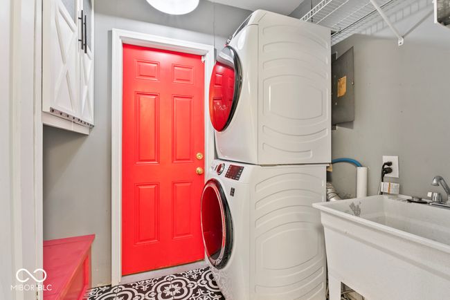 laundry room with stacked washer and dryer, cabinet space, and a sink | Image 27