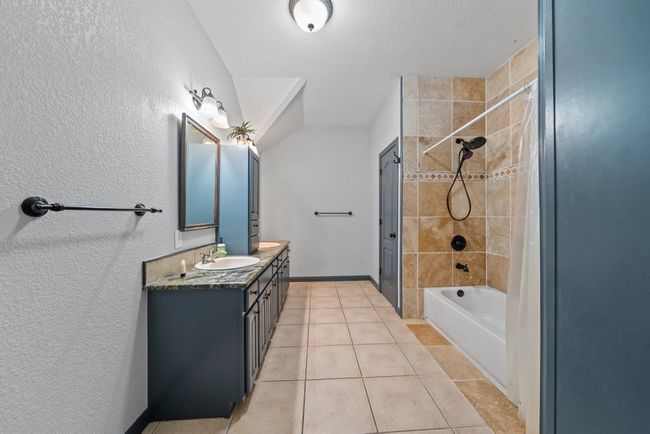 Bathroom featuring bathtub / shower combination, tile patterned flooring, a sink, baseboards, and double vanity | Image 22