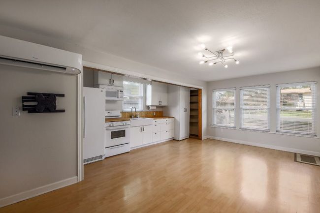 Kitchen with white appliances, a wall mounted AC, a sink, and baseboards | Image 23
