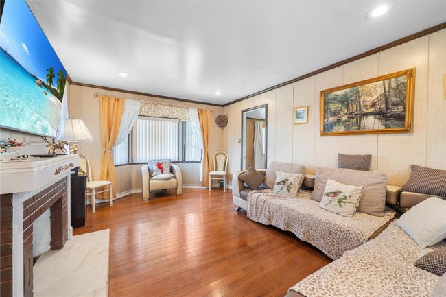 Living area with crown molding, wood finished floors, a brick fireplace, baseboards, and recessed lighting | Image 13
