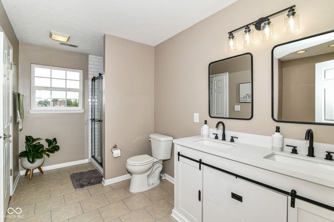 full bath featuring baseboards, toilet, double vanity, a shower with door, and tile patterned floors | Image 15