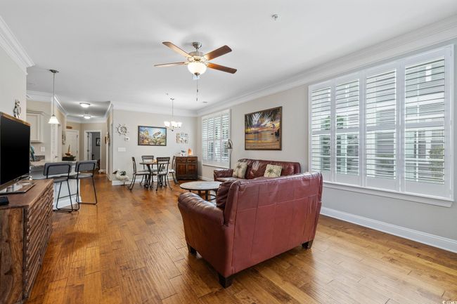 Living area featuring ceiling fan, wood-type flooring, baseboards, ornamental molding, and a chandelier | Image 13
