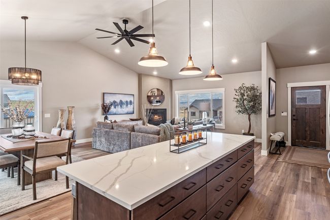 Kitchen featuring light wood-style floors, a fireplace, vaulted ceiling, dark brown cabinetry, and a kitchen island | Image 38