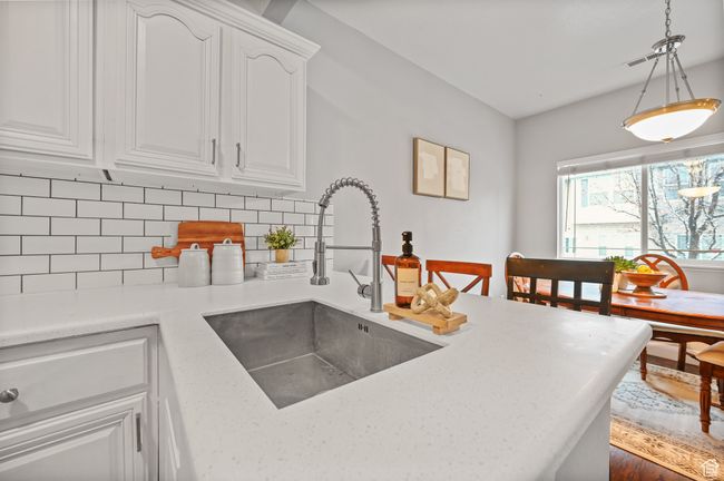 Kitchen featuring white cabinets, sink, hanging light fixtures, and tasteful backsplash | Image 7