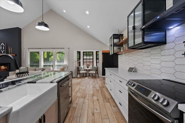 Sleek and modern kitchen with custom tile backsplash, floating shelves, and upgraded stainless steel appliances. | Image 21